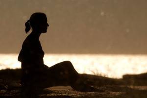 A woman sits of the beach at su