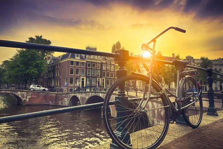 Sun beam coming through bicycle by water canal in Amsterdam.