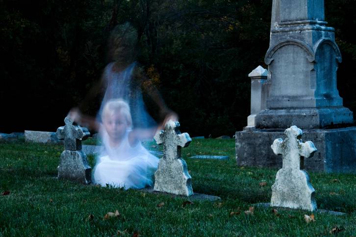 Ghost of young girl hovers between cross-topped gravestones