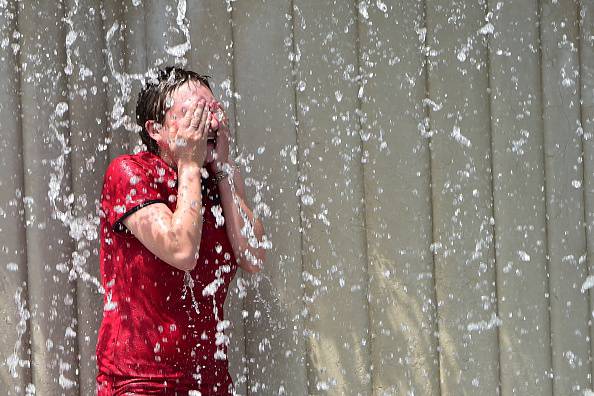 A tourist cools off in a fountain in Milan on July 4, 2015 as a major heatwave spreads throughout Europe with temperatures hitting nearly 40 degrees. AFP PHOTO / GIUSEPPE CACACE        (Photo credit should read GIUSEPPE CACACE/AFP/Getty Images)