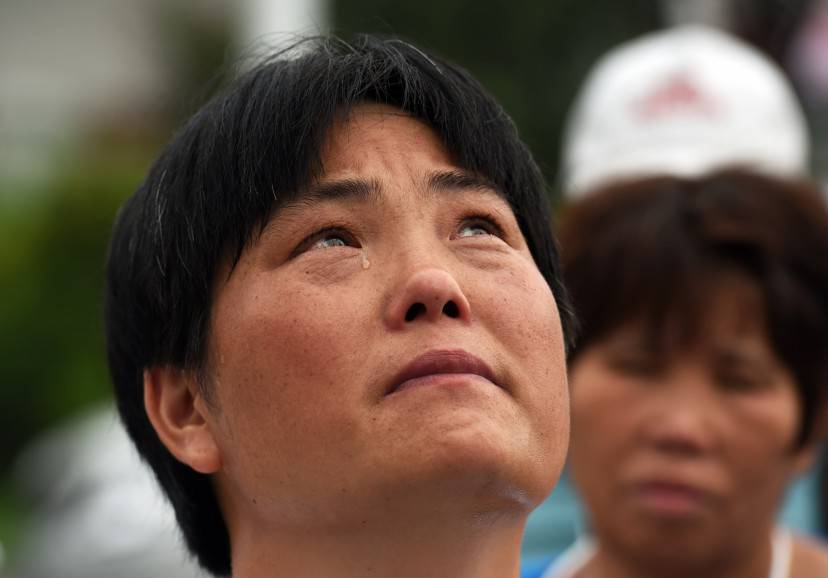 A relative of a passenger on missing Malaysia Airlines MH370 looks up as a plane passes overhead while waiting for an expected meeting with Malaysian officials outside an office near the airport in Beijing on August 7, 2015.  Debris found on a French remote island a week ago is from flight MH370, Malaysia's prime minister said, confirming that the plane which mysteriously disappeared 17 months ago met a tragic end in the Indian Ocean.     AFP PHOTO / GREG BAKER        (Photo credit should read GREG BAKER/AFP/Getty Images)