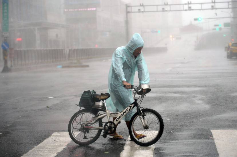 A man holds his bike as typhoon Soudelor hits Taipei on August 8, 2015.  Typhoon Soudelor battered Taiwan with fierce winds and rain leaving four people dead and a trail of debris in its wake as it takes aim at mainland China.  AFP PHOTO / Sam Yeh        (Photo credit should read SAM YEH/AFP/Getty Images)