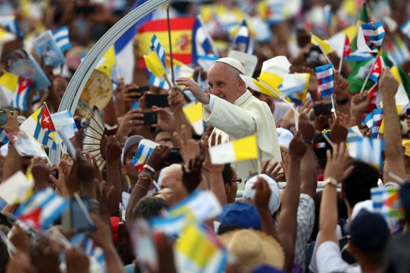 HAVANA, CUBA - SEPTEMBER 20:  People wave Cuban and Papal flags as Pope Francis passes by as he arrives to perform Mass on September 20, 2015 in Revolution Square in Havana, Cuba. Pope Francis is on the first full day of his three day visit to Cuba where he will meet President Raul Castro and hold Mass in Revolution Square before travelling to Holguin, Santiago de Cuba and El Cobre then onwards to the United States.  (Photo by Carl Court/Getty Images)