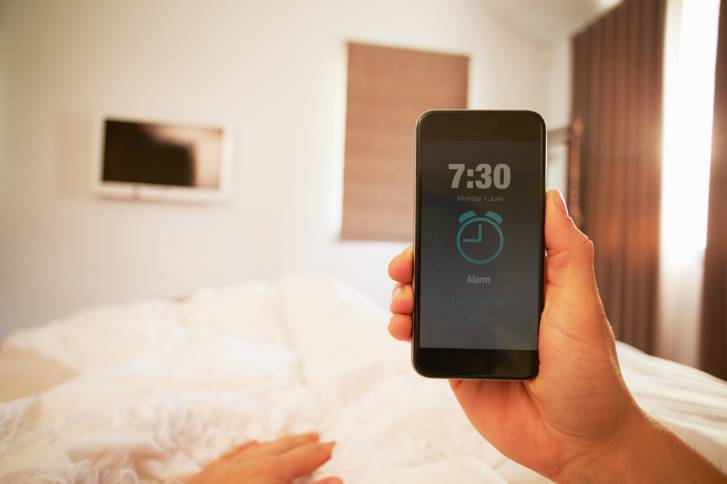 Person In Bed Turning Off Phone Alarm