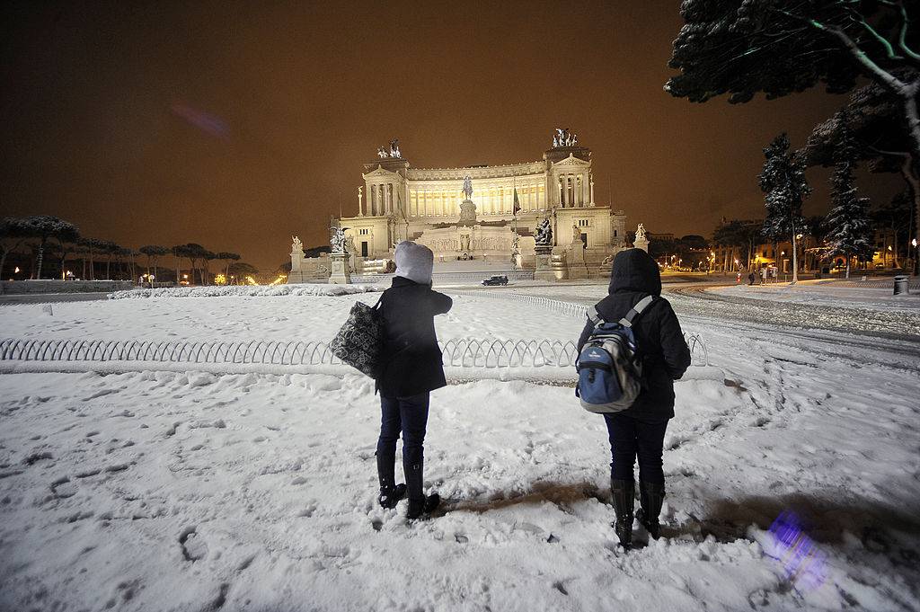 People stand on February 4, 2012 on Piazza Venezia in the center of Rome after a snowfall. A rare mantle of snow blanketed the historic center of Rome on February 3, forcing the closure of schools and tourist sites such as the Colosseum.    The snow covered palm trees, ancient Roman ruins and Baroque churches across the normally mild-weather Italian capital which has only seen one snowfall in the past 15 years in which the snow stayed on the ground for a whole day.  AFP PHOTO / FILIPPO MONTEFORTE (Photo credit should read FILIPPO MONTEFORTE/AFP/Getty Images)