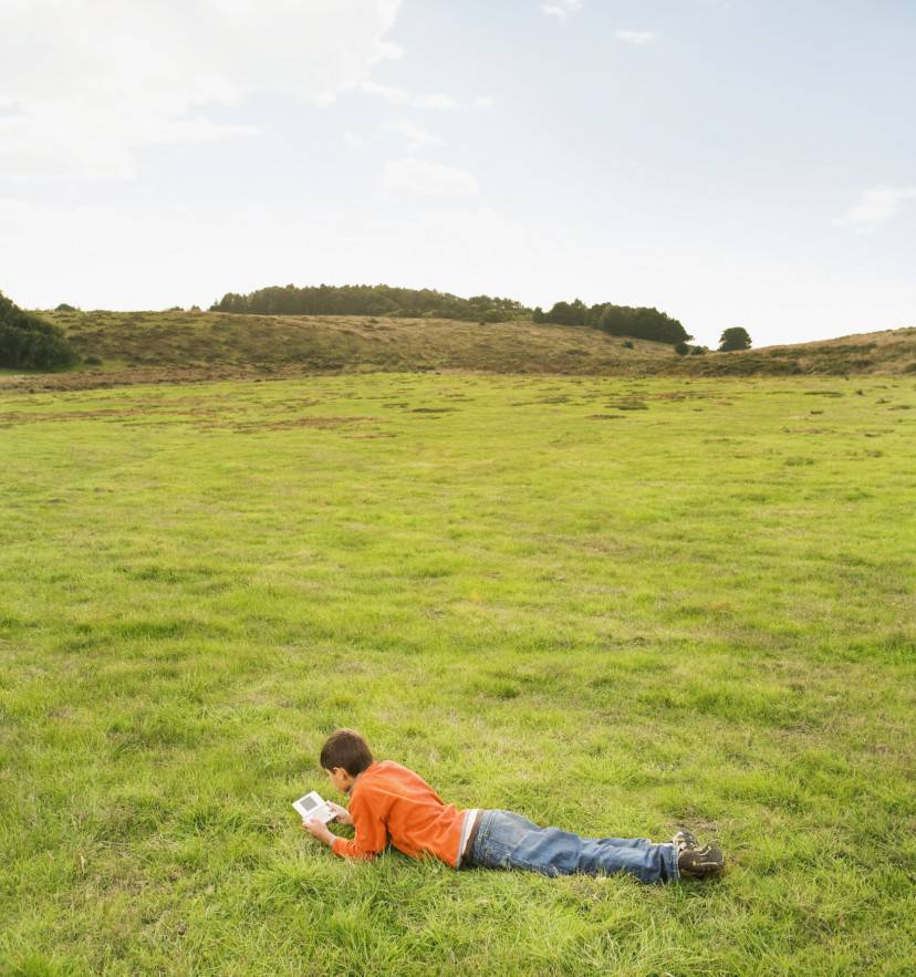Hispanic boy playing handheld video game in field