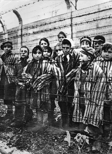 Children behind a barbed wire fence at the Nazi concentration camp at Auschwitz in southern Poland.   (Photo by Keystone/Getty Images)