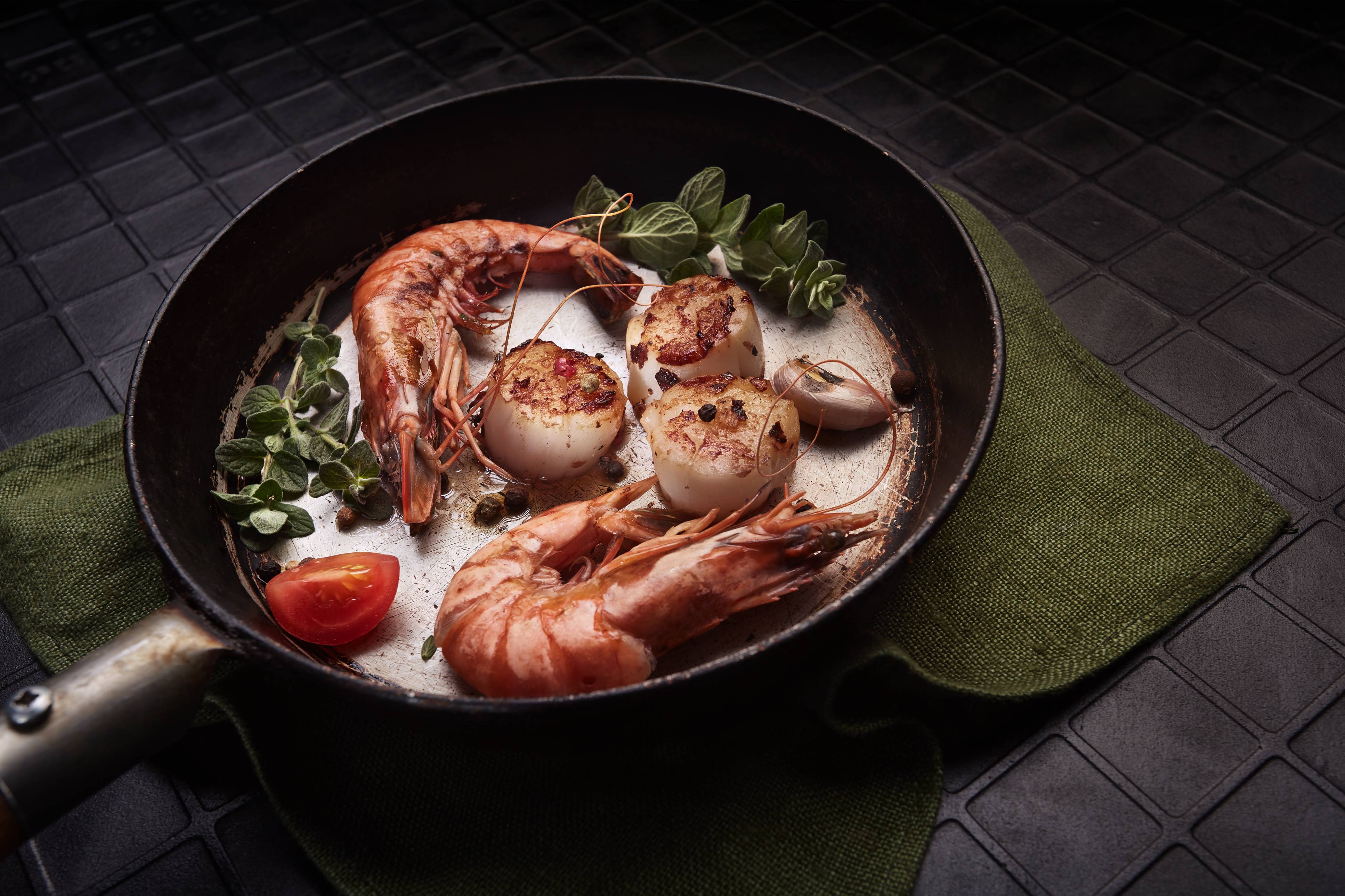 Shrimps and scallops on a old black pan