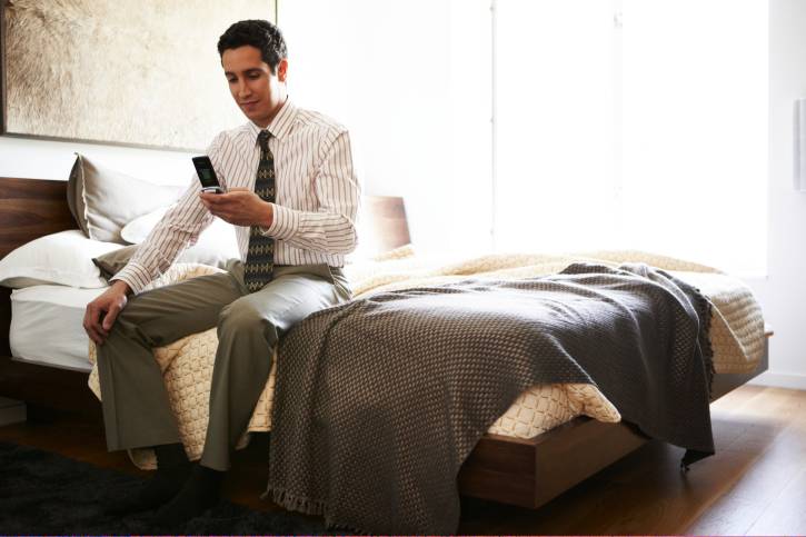 Latino man in hotel bedroom on mobile phone