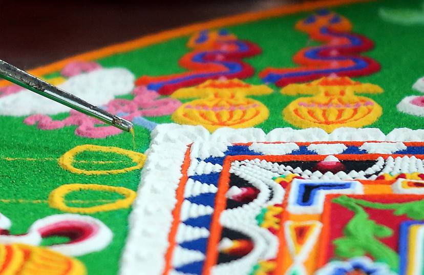 SALISBURY, ENGLAND - OCTOBER 03: A Tibetan Monk from the Tashi Lhunpo Monastery, helps complete a Chenrezig Sand Mandala in Salisbury Cathedrals Chapter House on October 3, 2013 in Salisbury, England. The monks, who started the painstaking process of creating the sand mandela with millions of grains of coloured sand on Monday, will end it tomorrow in a destruction ceremony and procession to the River Avon. The monks who currently live in exile in India are visiting various places in the UK and Europe and will complete two more sand mandelas - which are an artistic tradition of Tibetan Buddhism and are a symbolic picture of the universe representing an imaginary palace - before returning home to their monastery in late November. (Photo by Matt Cardy/Getty Images)