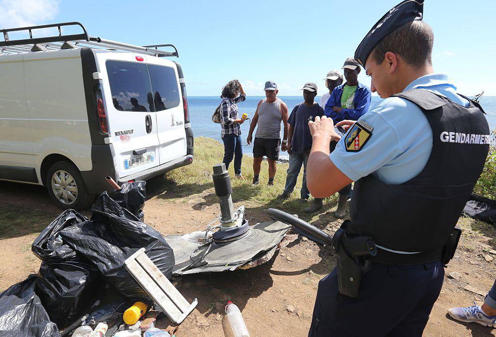 A French Gendarme (R) takes a picture of debris gathered by members of local ecological associations and volunteers on August 11, 2015 in the eastern part of Sainte-Suzanne, on France's Reunion Island in the Indian Ocean, during search operations for the missing MH370 flight conducted by French army forces and local associations. The hunt for more wreckage from the missing MH370 resumed on Reunion island on August 9 after being suspended due to bad weather, local officials said. A wing part was found on the island in late July and confirmed by the Malaysian prime minister to be part of the Boeing 777 which went missing on March 8, 2014 with 239 people onboard. AFP PHOTO / RICHARD BOUHET (Photo credit should read RICHARD BOUHET/AFP/Getty Images)