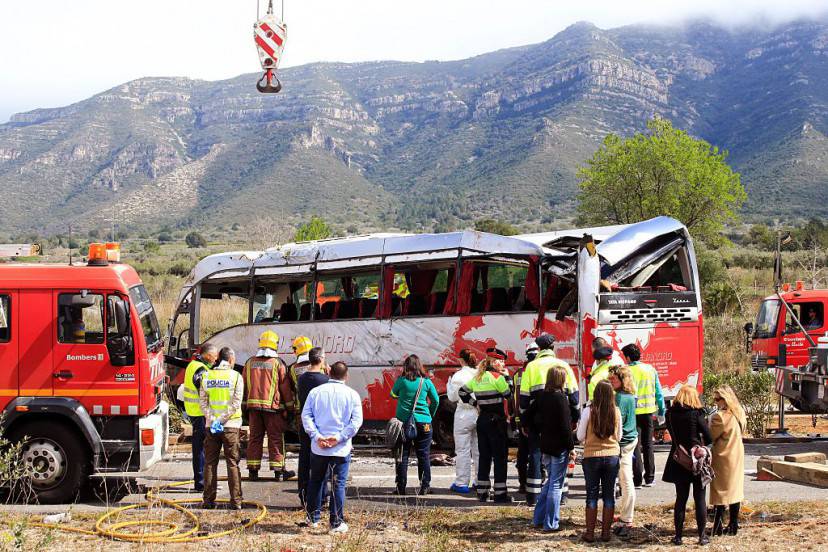 Emergency personnel stand before the righted bus on the Spanish AP-7 motorway near Freginals,  Amposta south of Tarragona following a fatal  accident that claimed the lives of 13 foreign students an injured 44 others early on March 20, 2016. The students, enrolled at Barcelona University as part of the European Erasmus exchange programme, were returning from a traditional festival in the eastern city of Valencia when the driver "hit the railing on the right and swerved to the left so violently that the bus veered onto the other side of the highway," Jordi Jane,who heads interior matters for the Catalonia region, said. / AFP / PAU BARRENA        (Photo credit should read PAU BARRENA/AFP/Getty Images)
