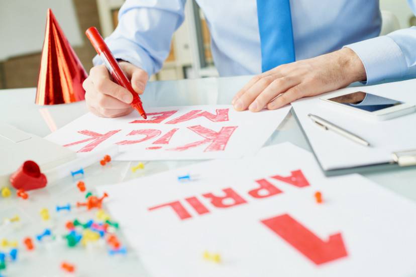 Hands of office worker writing kick me sign on April Fools Day