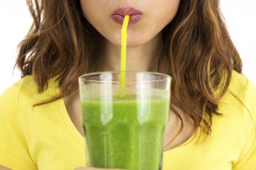 Close up of woman drinking green smoothie. Isolated on white background.