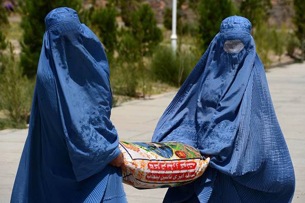 Donne afghane con il burqua mentre portano un sacco con aiuti alimentari a Herat (AREF KARIMI/AFP/Getty Images)