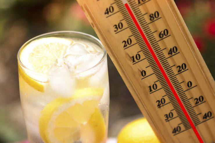Warm summer day, thermometer next cold lemonade  showing high temperature