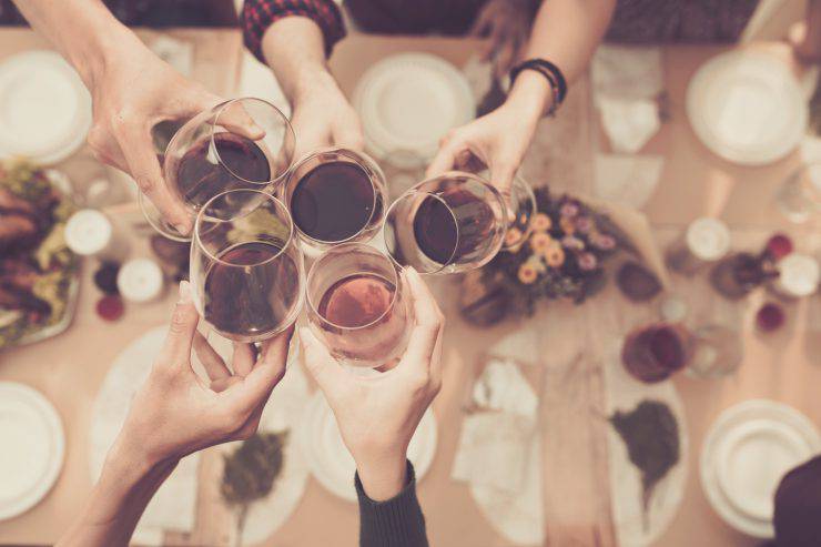 Friend clinking glasses above dinner table