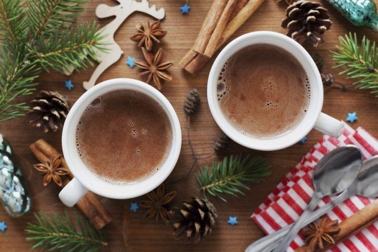 Two cups of fresh hot cocoa or hot chocolate on wooden christmas background, top view