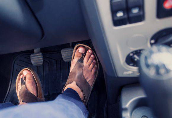Guidare con le ciabatte Uomo schiaccia pedali della sua auto indossando le infradito