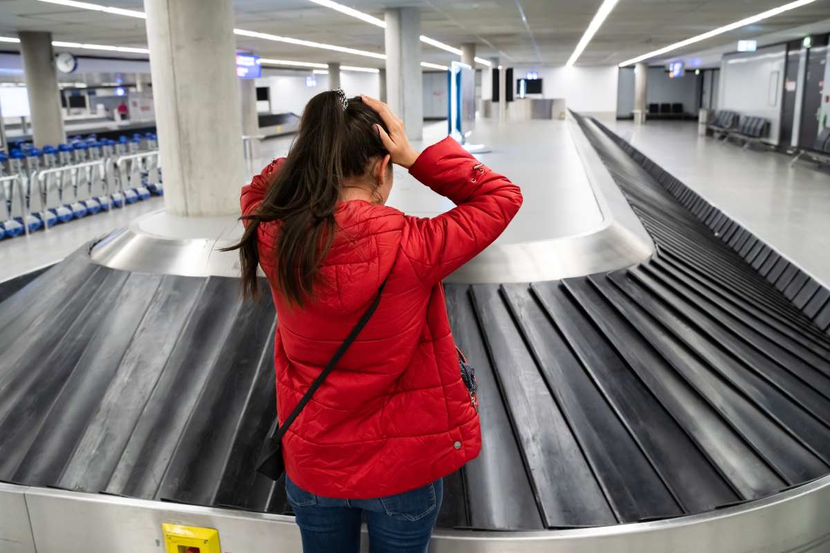 Donna cerca il suo bagaglio al nastro trasportatore