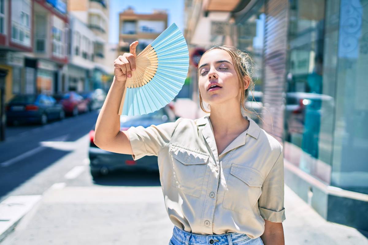 Sudi e senti più caldo degli altri? È normale Donna con ventaglio sente molto caldo