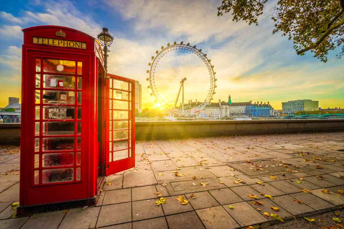 Cabine telefoniche rosse di Londra con sfondo il London Eye al tramonto