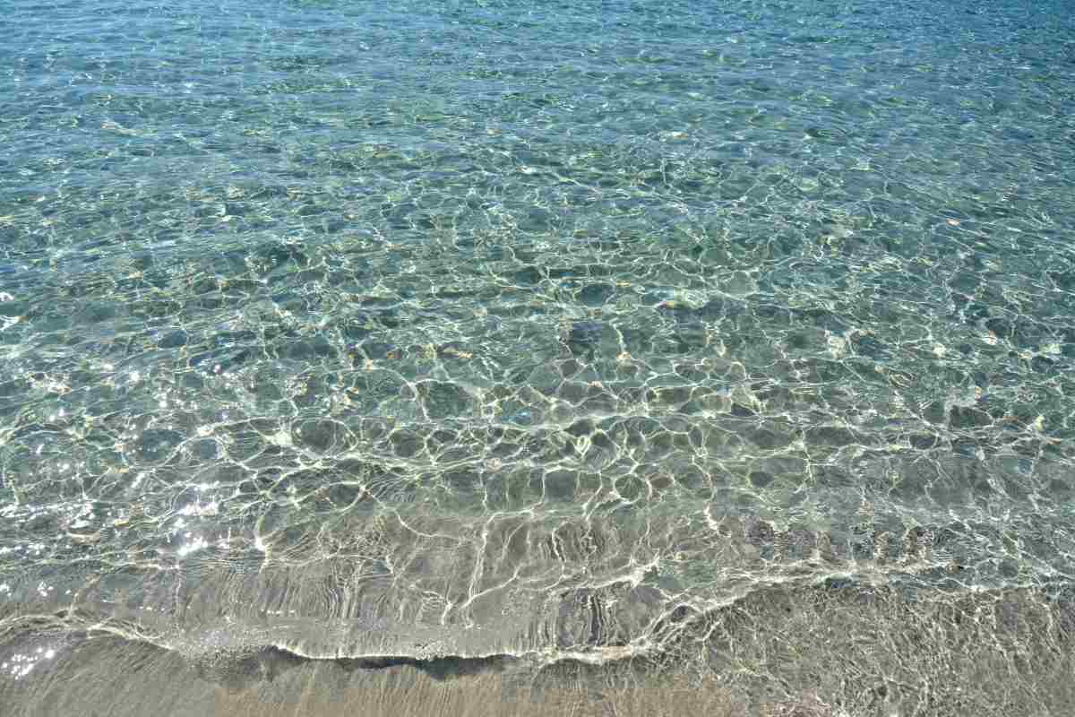 mare trasparente che si infrange sulla riva di sabbia