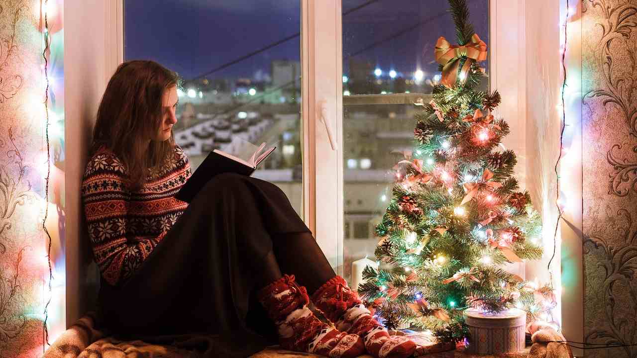 Ragazza legge accanto all'albero di Natale