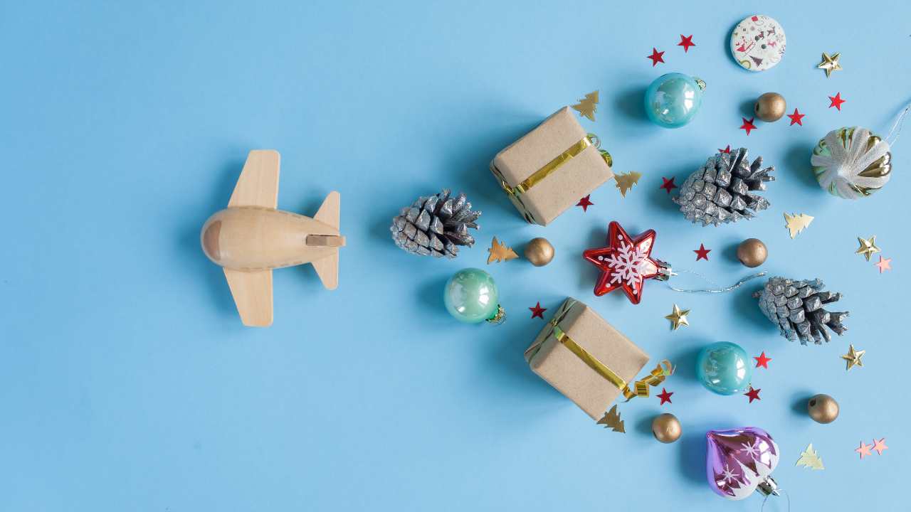 Aereo giocattolo con decorazioni natalizie su sfondo azzurro