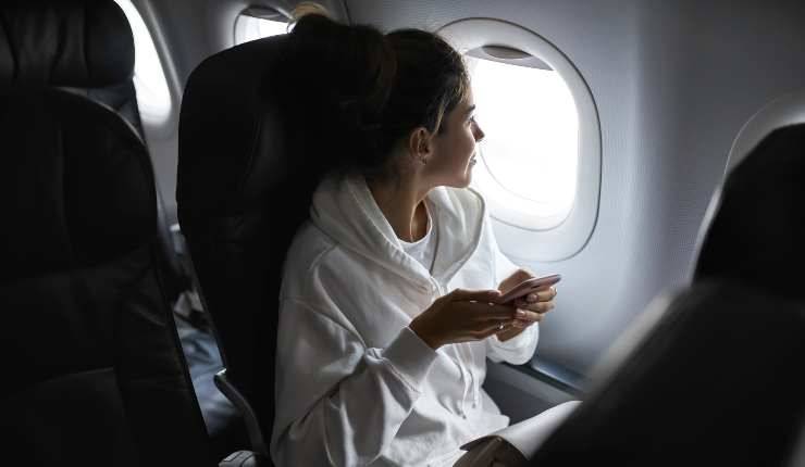 Ragazza con cellulare in mano durante un volo aereo