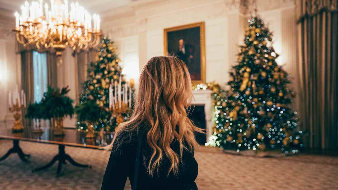 Ragazza guarda due alberi di Natale in un salotto