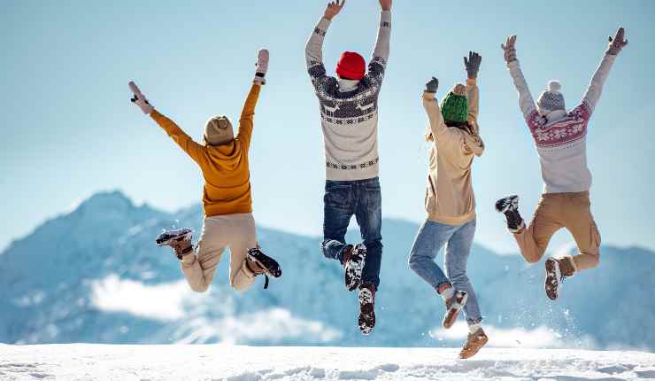 Famiglia salta felice nella neve durante le vacanze di Natale in montagna