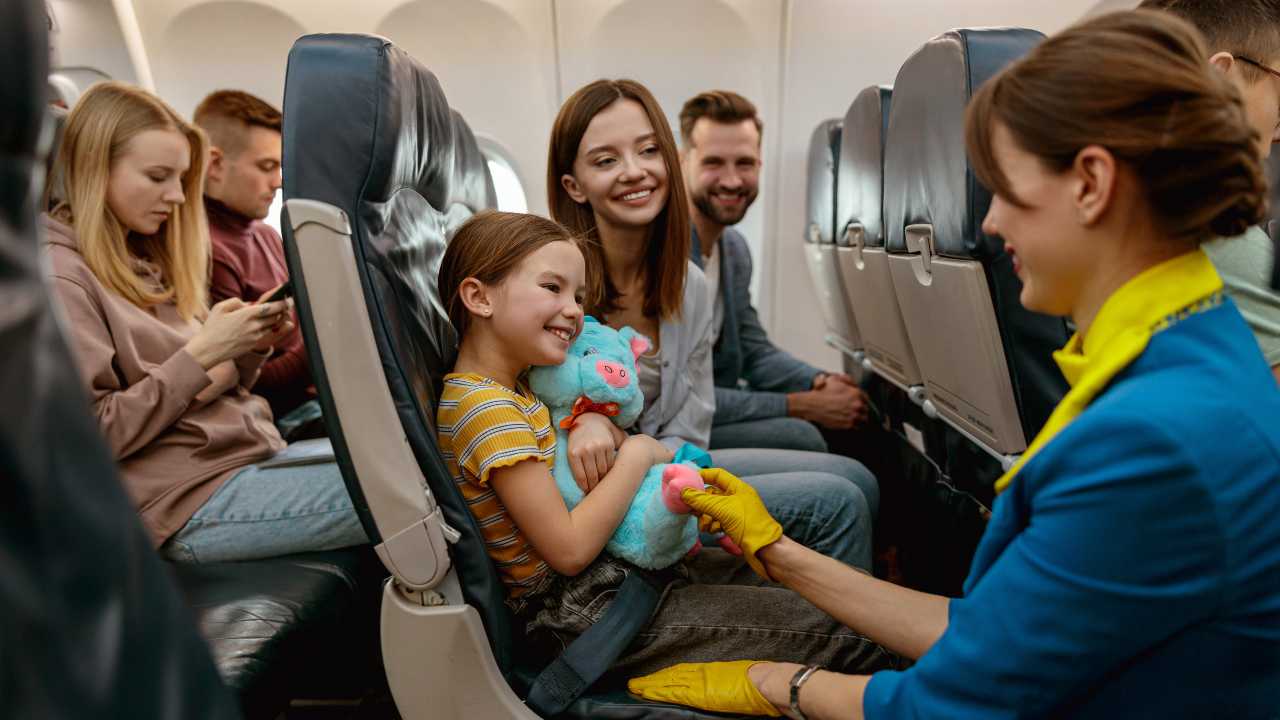 Bambina in aereo con hostess e la sua famiglia