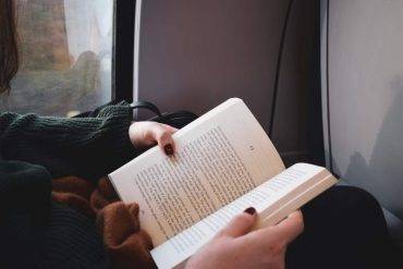 Le mani di una ragazza che legge un libro in treno