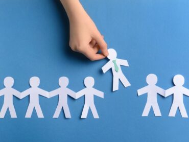 Mano che toglie un omino di carta dalla catena origami: illustrazione licenziamento