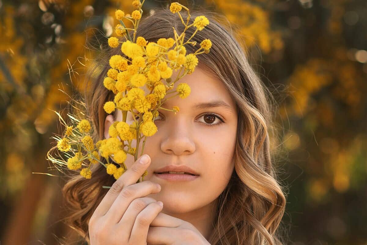 ragazza con mazzetto di mimosa vicino al viso