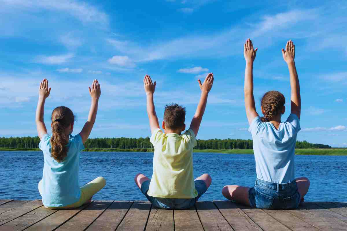 bambini di spalle che alzano le braccia al cielo
