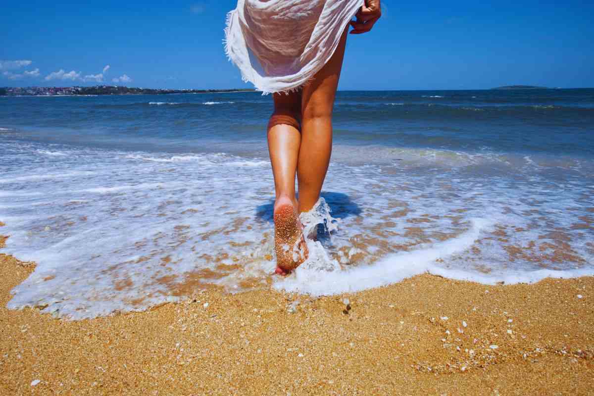 Donna che bagna i piedi sulla battigia