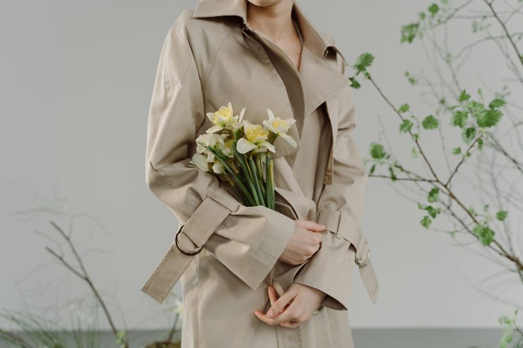 Ragazza indossa un trench e tiene in mano dei fiori
