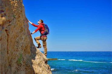 Ragazza che fa arrampicata con sfondo mare