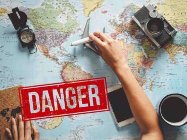 mappamondo con oggetti di viaggio e scritta danger