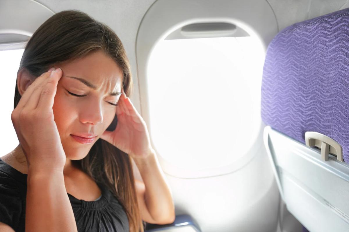 Donna in aereo con le mani sulle tempie