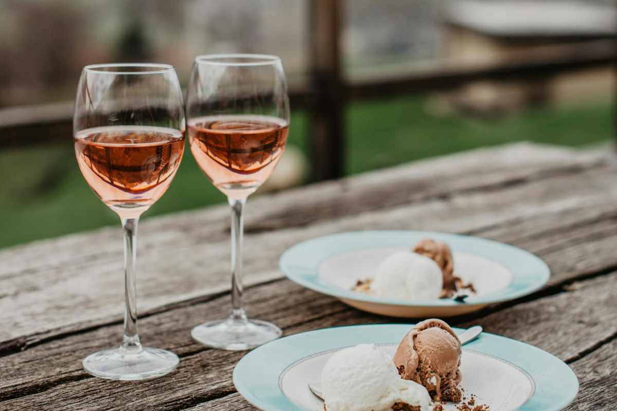 Bicchieri di vino e piatti con gelato poggiati su un tavolo di legno