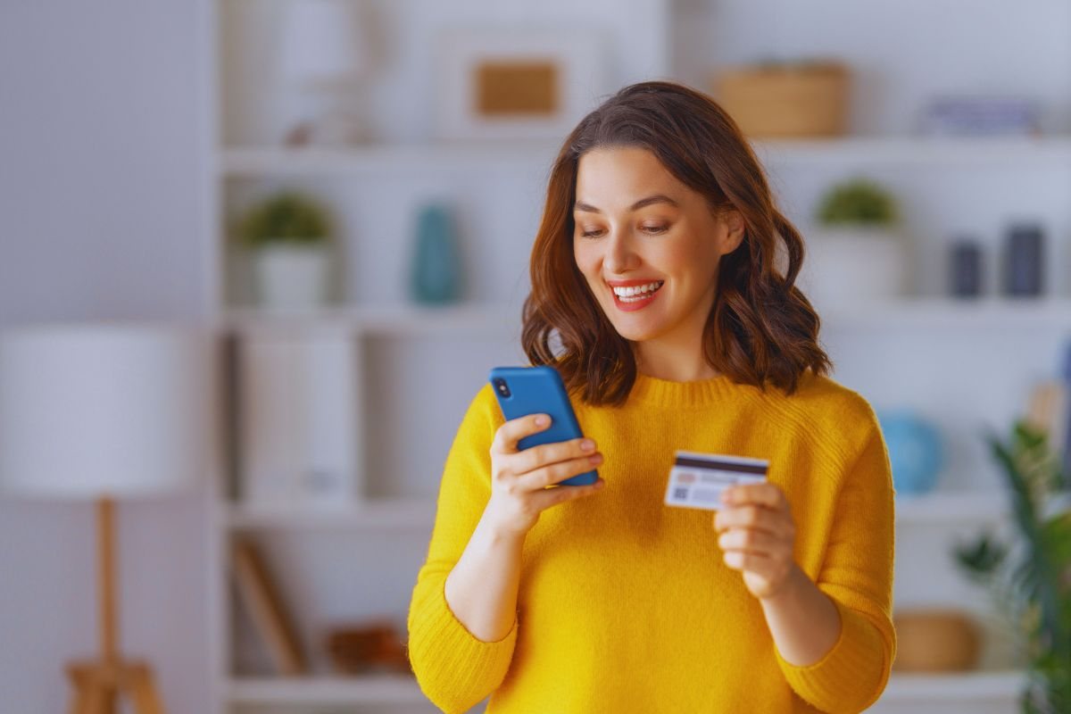 Ragazza felice che scrive i dati della carta su smartphone