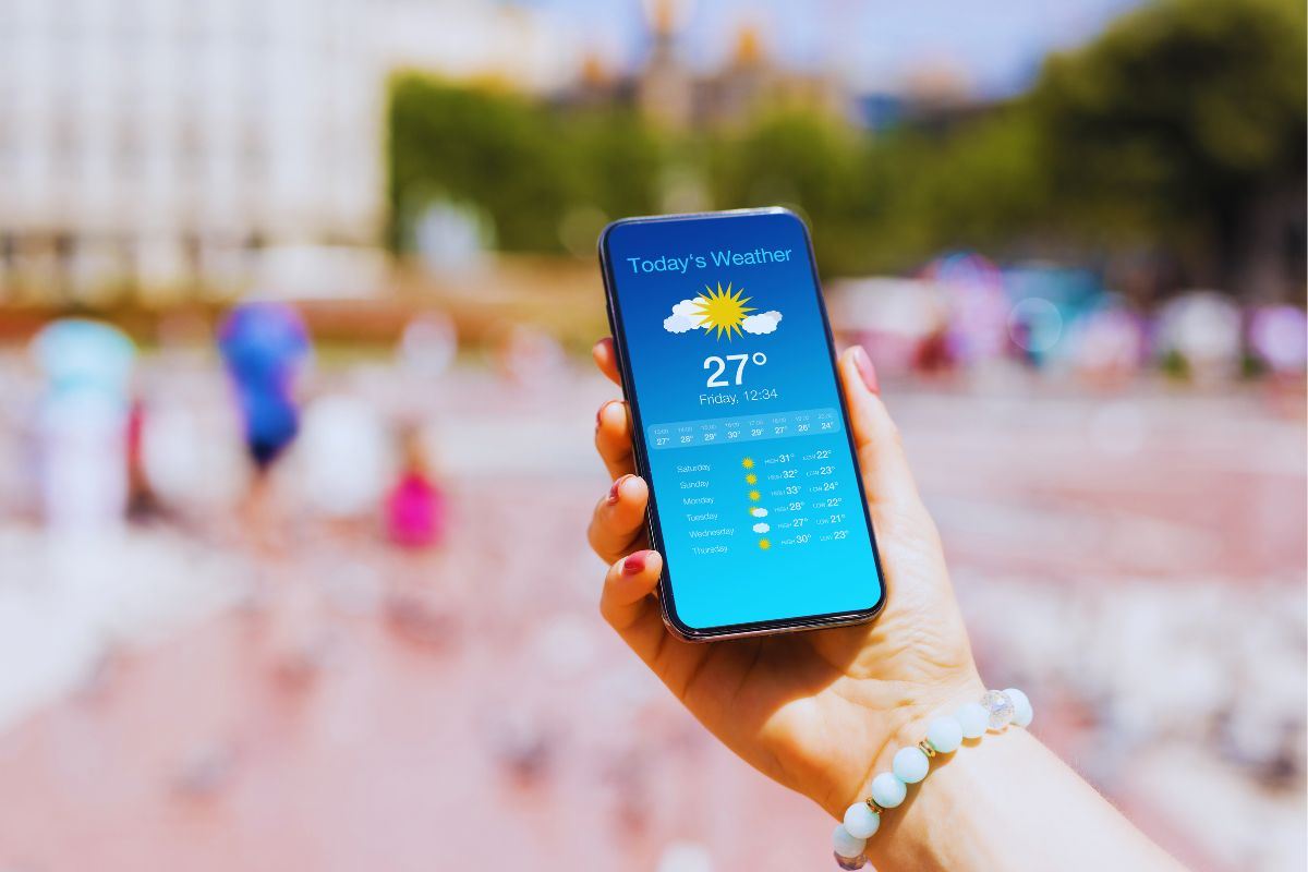 Donna in spiaggia che guarda app meteo sullo smartphone