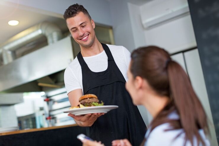 Cameriere porge piatto con hamburger alla cliente