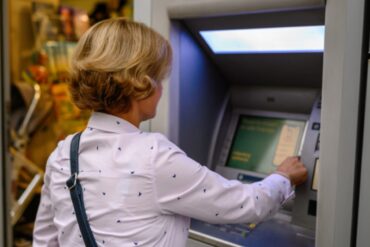 donna che difita il codice sulla tastiera dello sportello bancomat