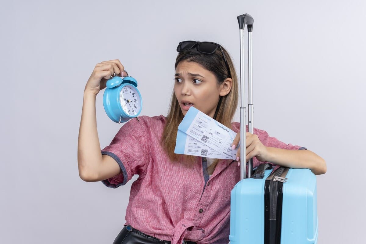 Ragazza che guarda una sveglia mentre tiene la valigia e i biglietti per l'aereo