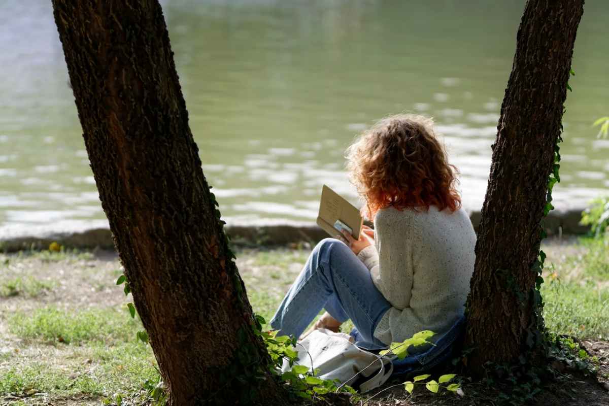 Donna che legge un libro sulle rive di un lago