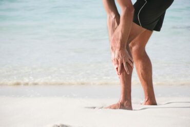 Uomo al mare che si tiene la gamba